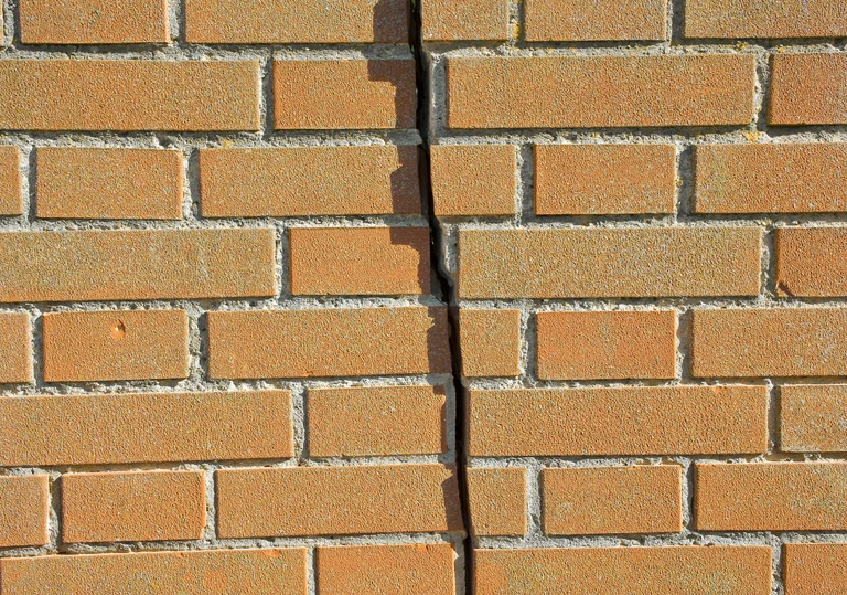 Pionowe pęknięcie konstrukcyjne w&nbsp;murze z&nbsp;cegły klinkierowej