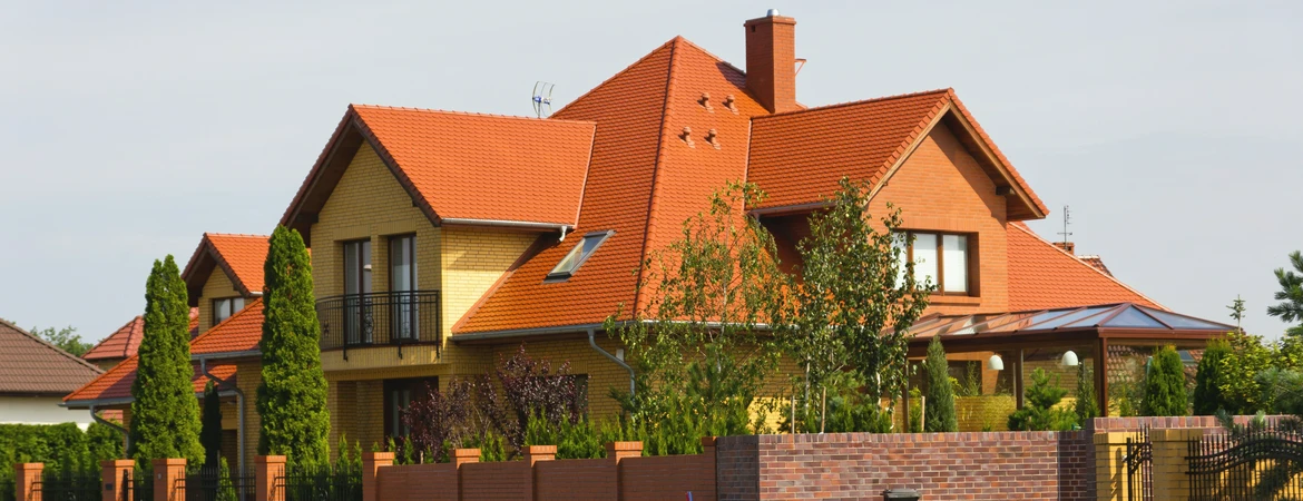 Duży, nowoczesny dom jednorodzinny z&nbsp;wielospadowym dachem pokrytym czerwoną dachówką